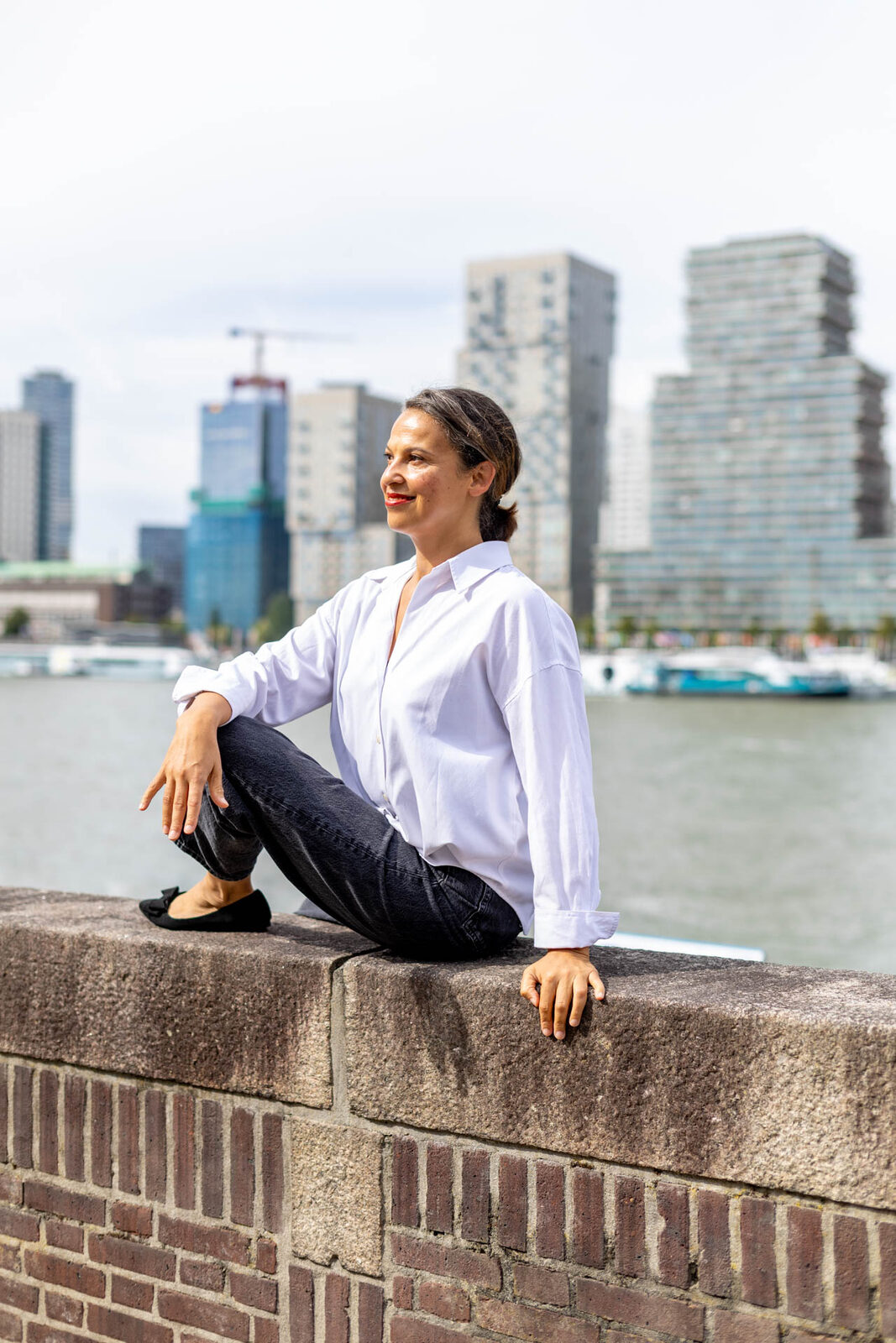 Danielle buiten aan de Maas, met de Rotterdamse skyline op de achtergrond